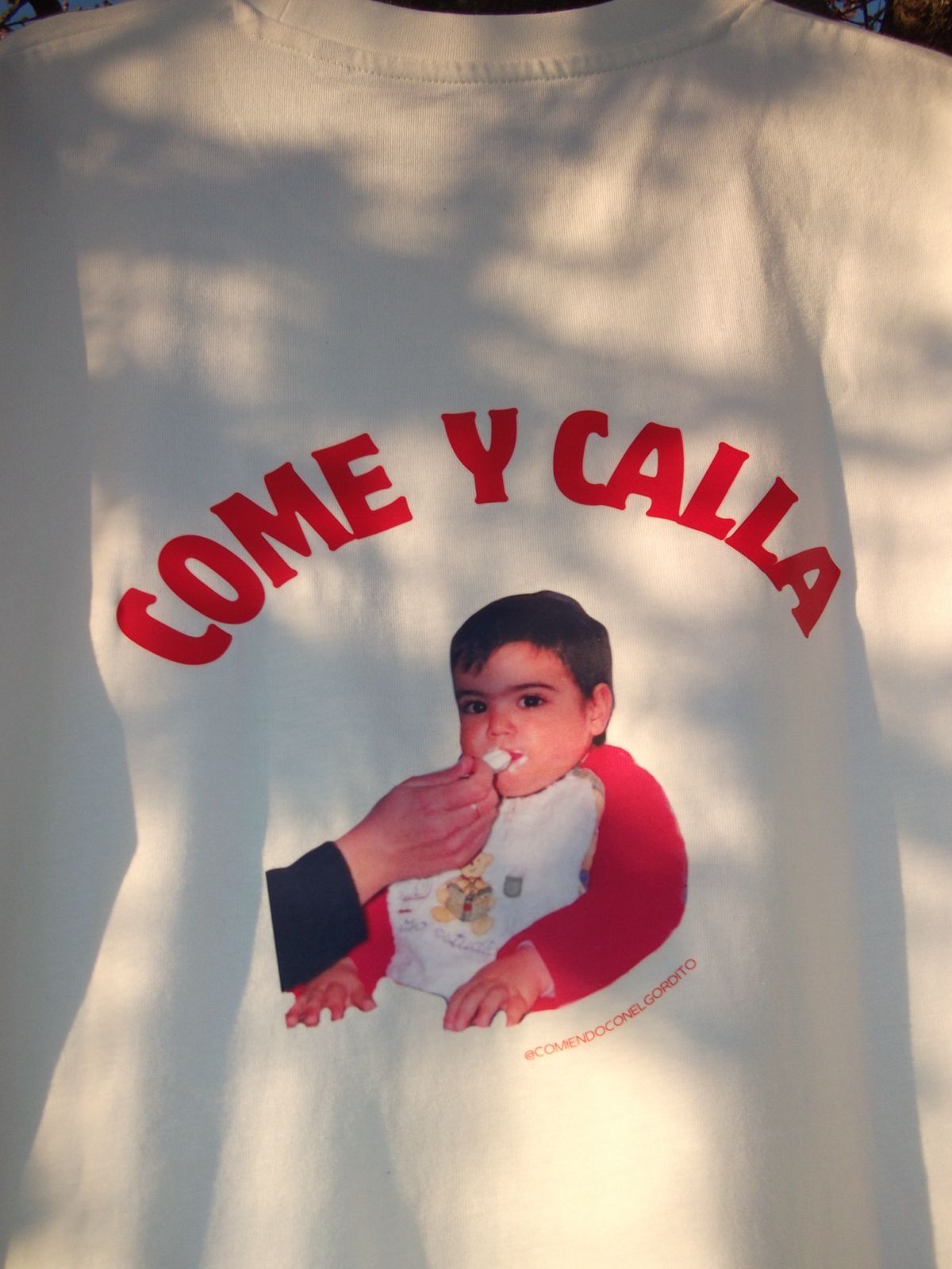 Espalda de la camiseta de la marca con el lema Come y calla