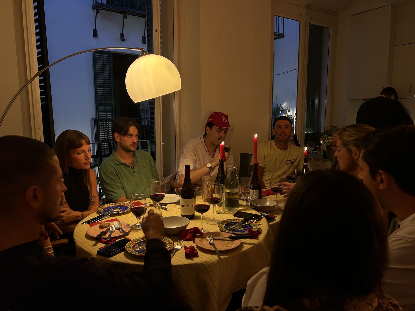 Cena de grupo alrededor de una mesa redonda con velas, de noche