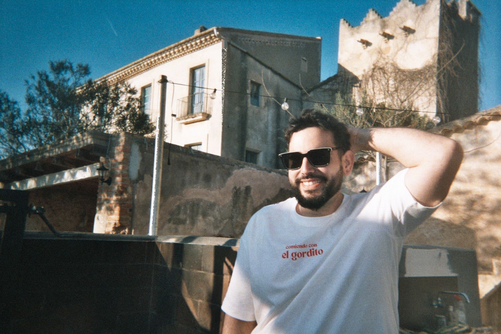 El Gordito, sonriendo con gafas de sol y la camiseta de la marca, delante de una masía